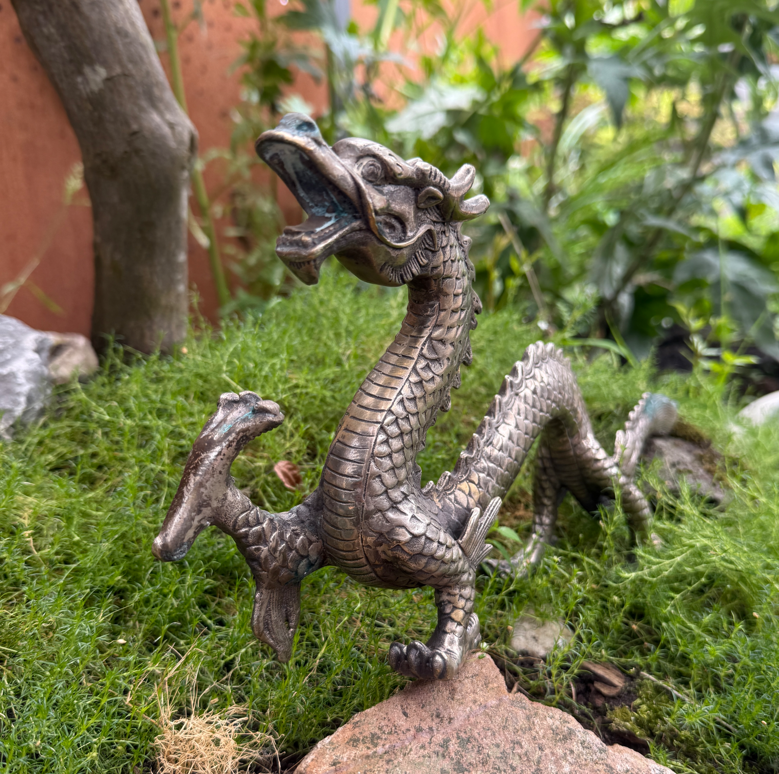 Silver Japanese dragon sculpture, Meiji period style, ornate details on green moss, katana category.