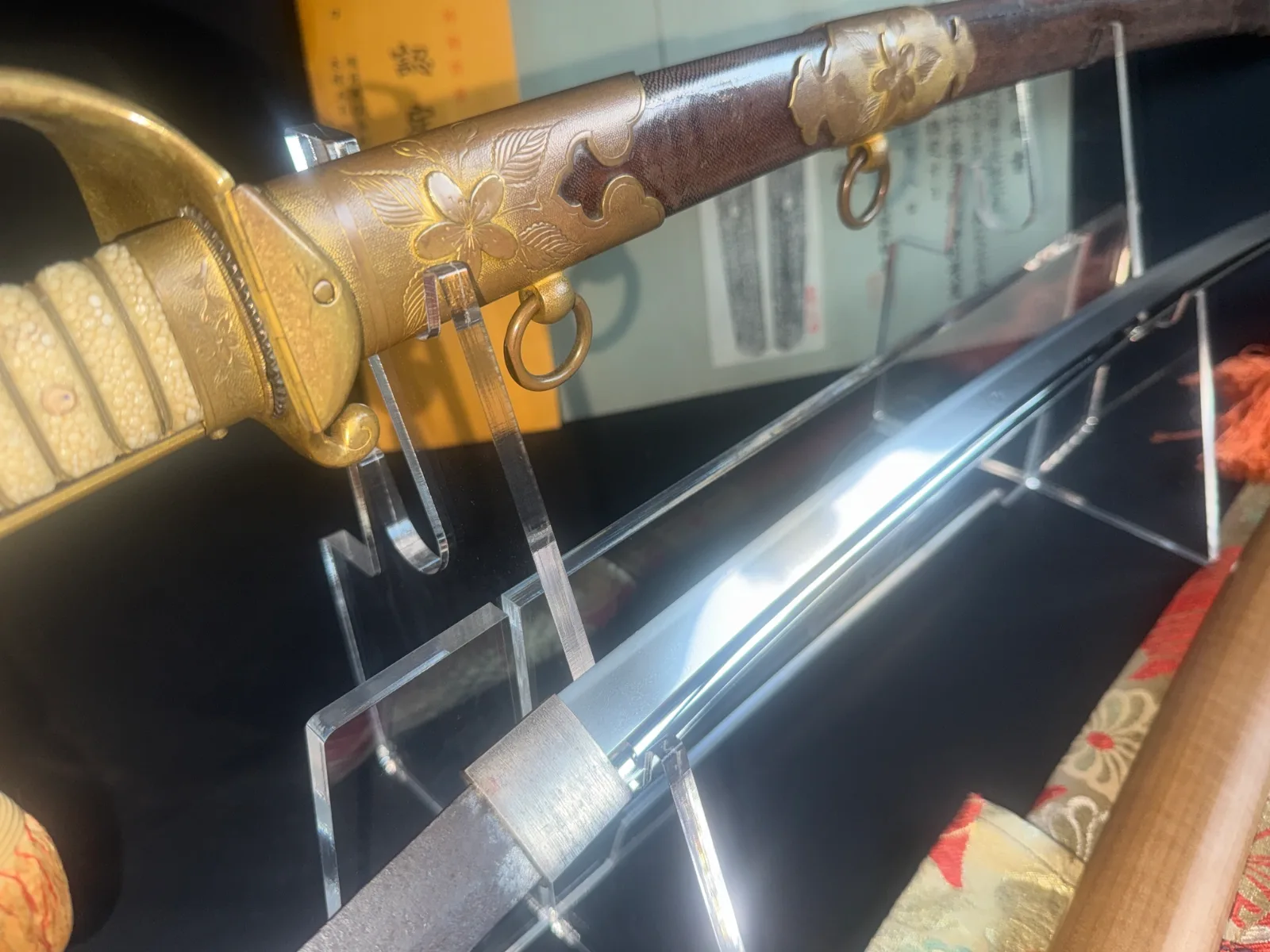 Naruse Family Heirloom katana hilt and blade. Close-up of gold guard, white handle, brown scabbard with sakura motifs.