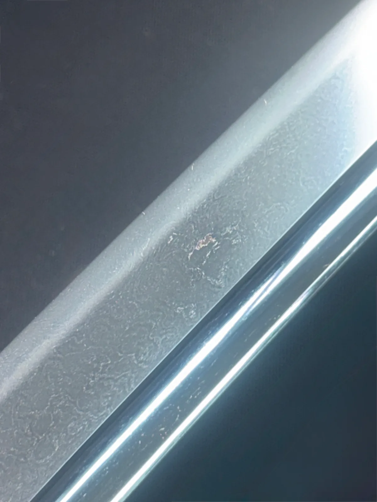Close-up of the Naruse Family Heirloom katana blade showing a detailed view of its visible hamon and steel grain.