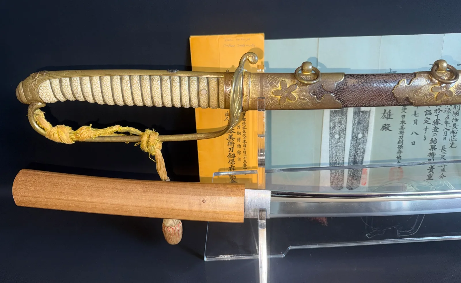 Naruse Family Heirloom katana with Naval Kyū Guntō Koshirae, partial blade shown, paperwork behind.
