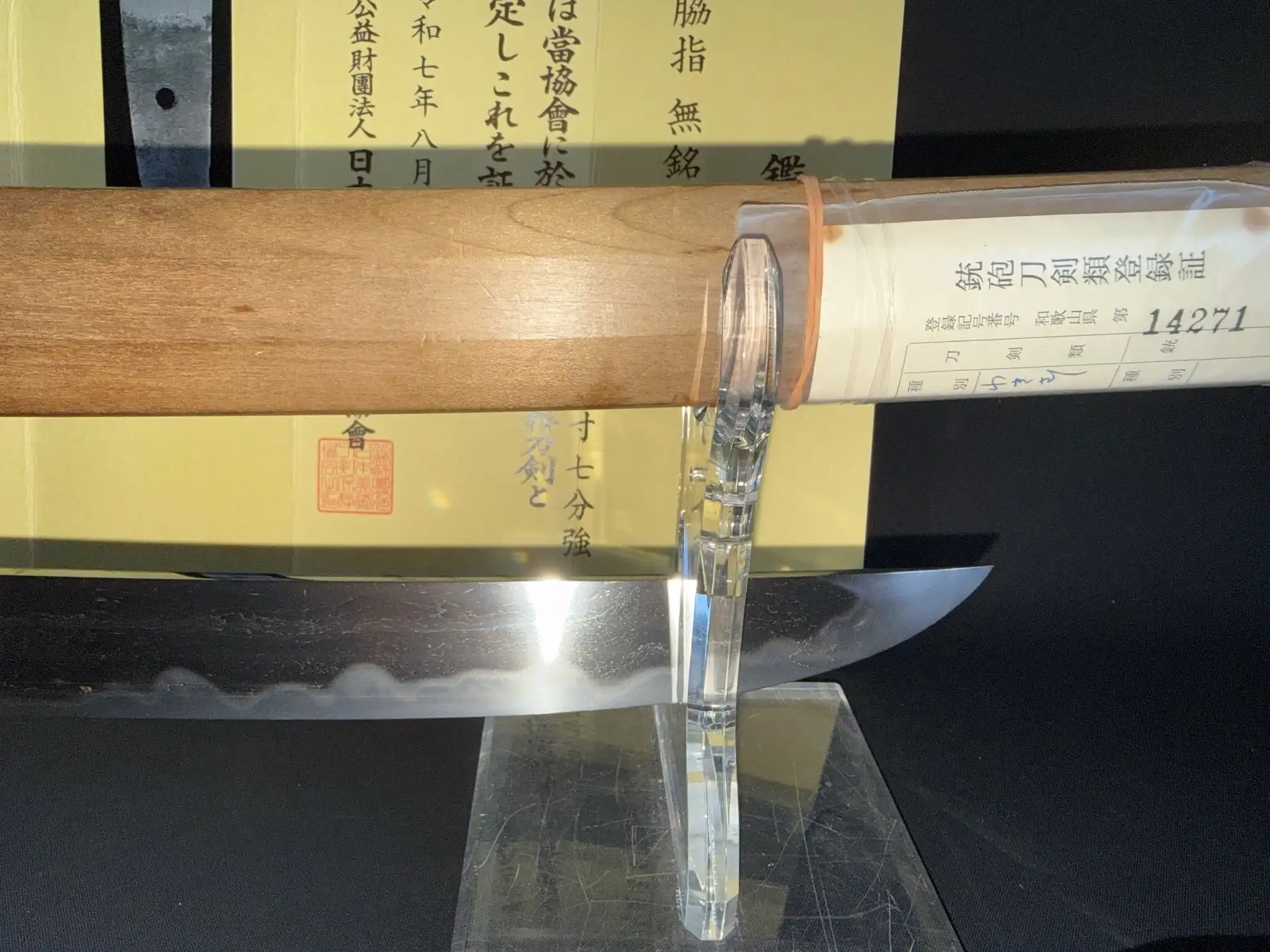 Koto Mumei Wakizashi Sengo Muramasa, blade visible on stand with tang in wooden shirasaya and papers