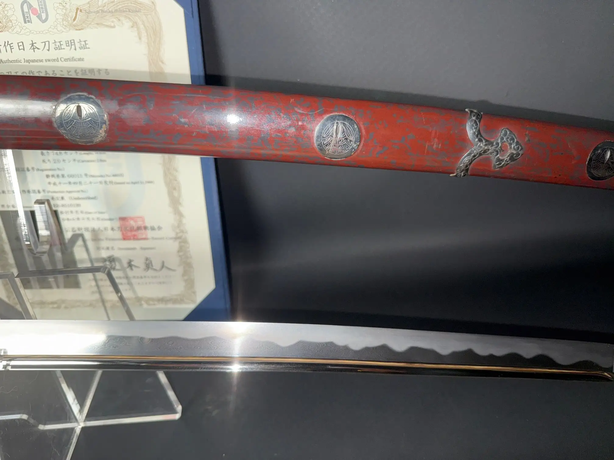 Close-up of Tachi Katana Sadayoshi/Sadahito, showing red saya with silver accents, and the polished blade.