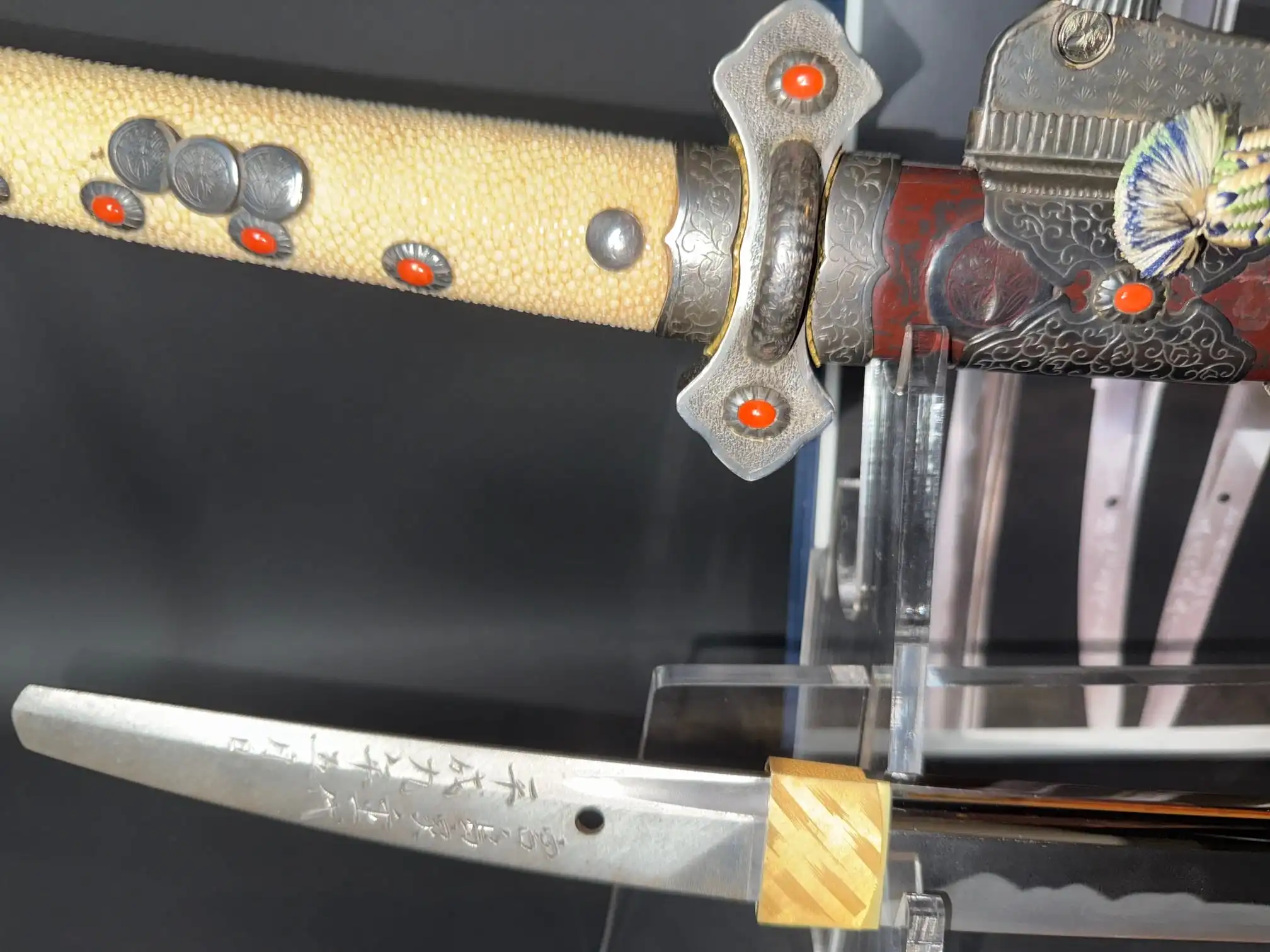 Close-up of a Tachi Katana Sadayoshi/Sadahito, showing a ray skin handle with red accents and the engraved blade.