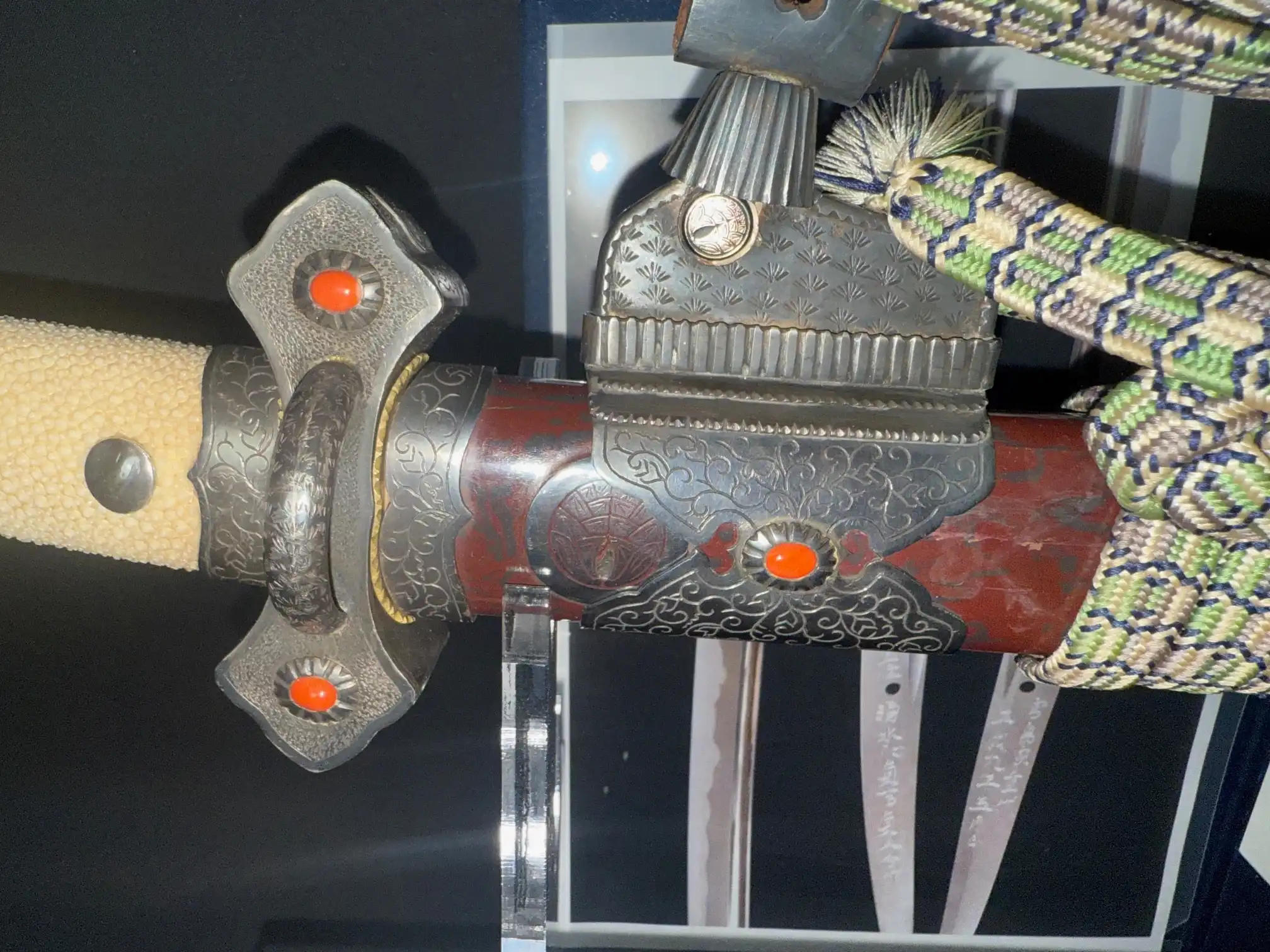 Detailed close-up of a Sadayoshi/Sadahito Tachi Katana, showcasing red lacquered saya and decorative metal fittings