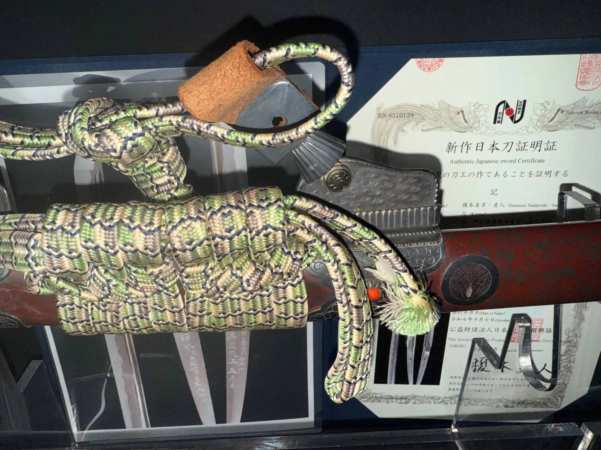 Close up of the Tachi Katana Sadayoshi/Sadahito, showing a tightly wrapped tsuka with certificate in background