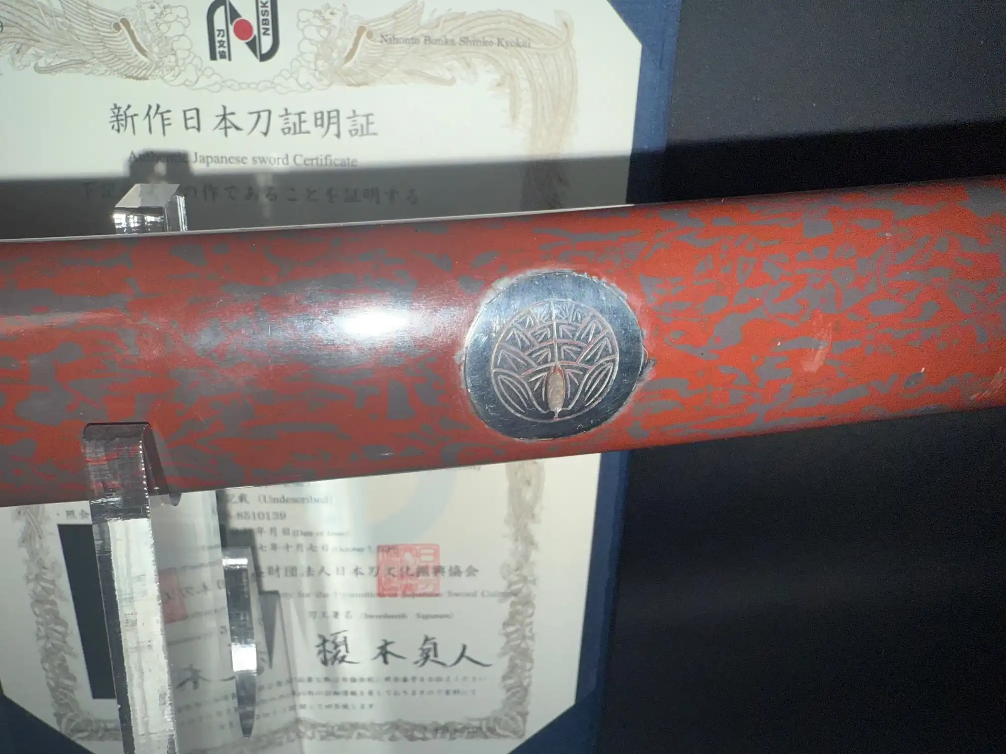 Close-up of Tachi Katana Sadayoshi/Sadahito, a Japanese sword with a detailed saya and emblem, certificate visible.