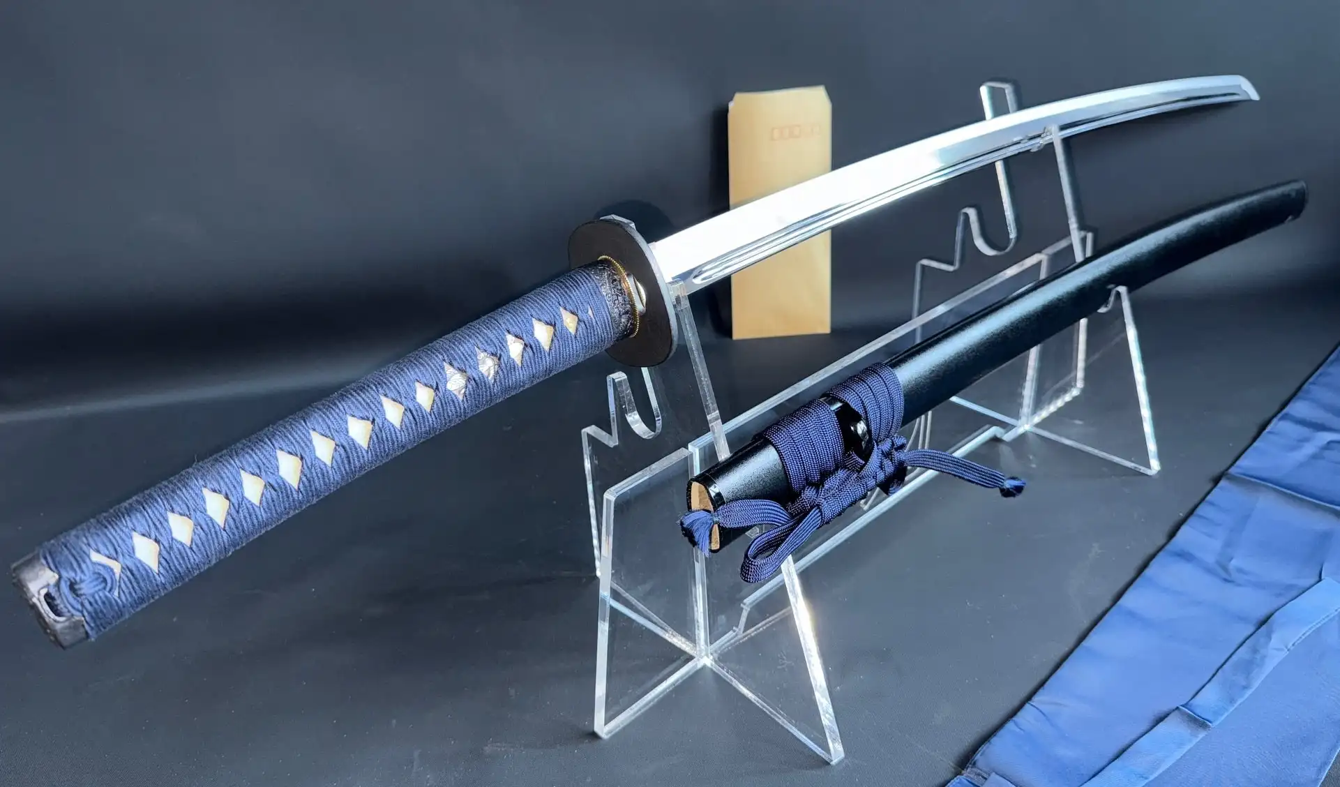 IAITO MINOSAKA TOKUSEI Japanese Iaido sword: blue tsuka and black saya on a clear stand, angled view